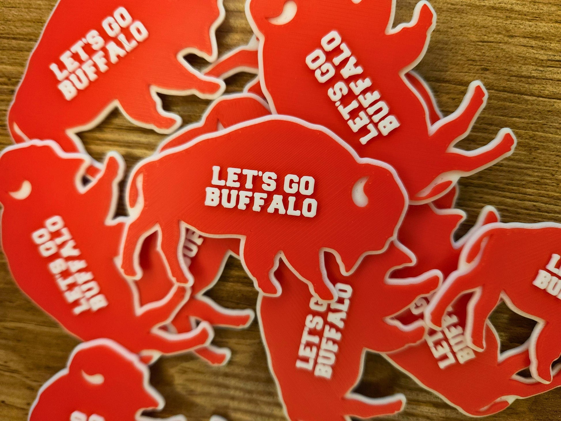 Pile of red Lets Go Buffalo magnets stacked on a wooden surface.