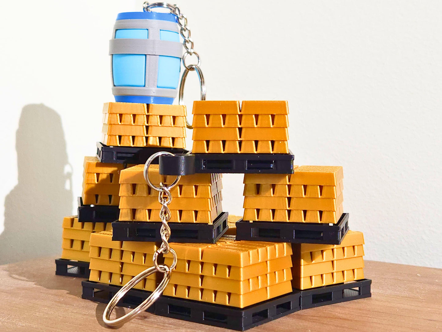A close up picture of a set of many gold bar keychains and a single Chug Jug keychains from Fortnite. The top has a mechanical clicker that can be used for anti-stress or as a fidget toy.