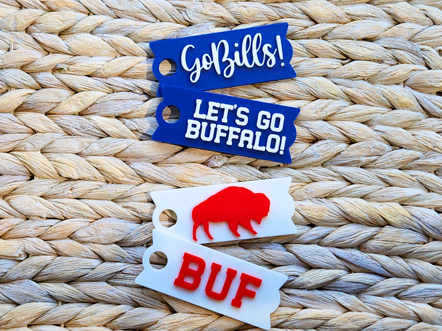 Set of four Buffalo Bills-themed Stanley cup toppers displayed on a woven mat, including designs that say Go Bills!, Let’s Go Buffalo!, BUF in red letters, and a red buffalo silhouette.