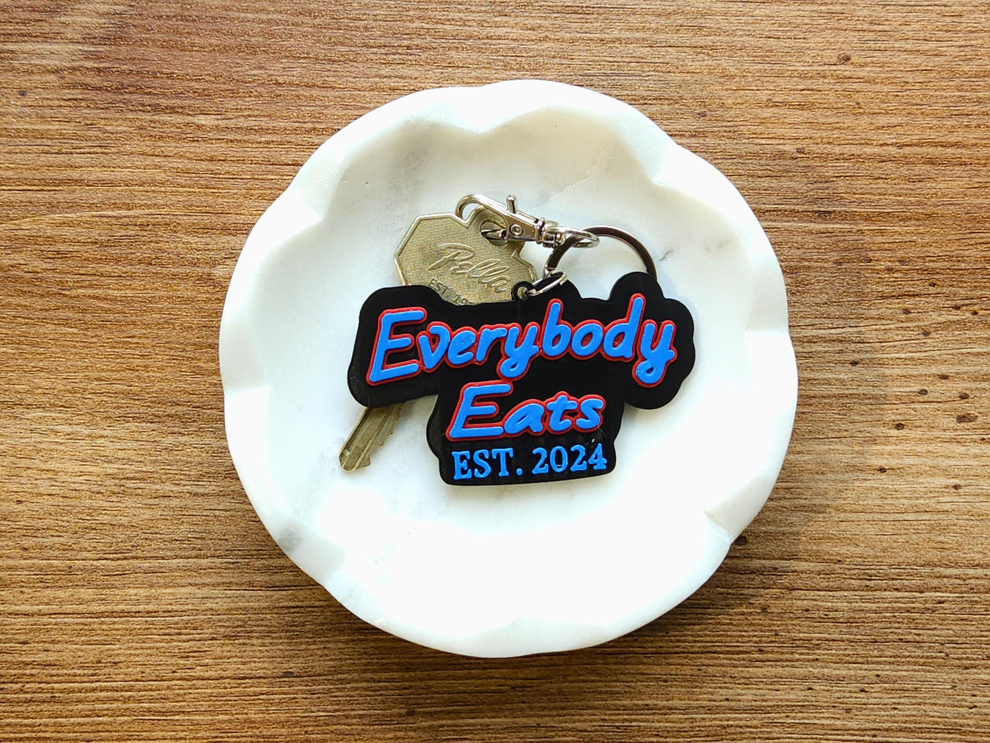 Everybody Eats Est. 2024 Buffalo Bills keychain on white ceramic dish, featuring bold red and blue text on black 3D printed base – football fan gift