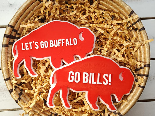 2 Retro Buffalo Bills magnets pictured in a basket. One says Let's Go Buffalo and the other says  Go Bills in raised white letters on a bright red background.