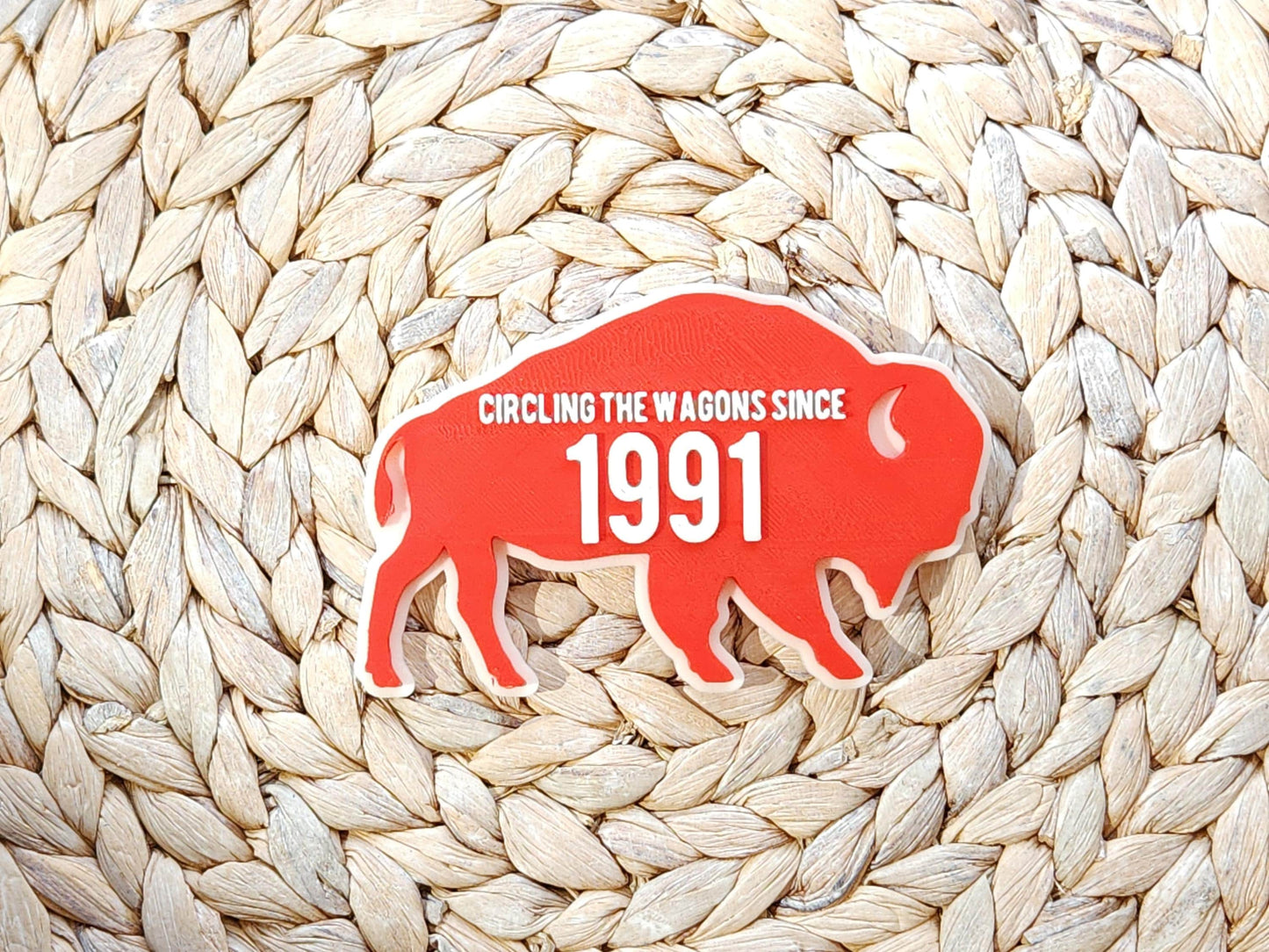 A red magnet for Buffalo Bills fans that says Circling the Wagons since 1991 that can be customized with any year. It is shown on a woven background.