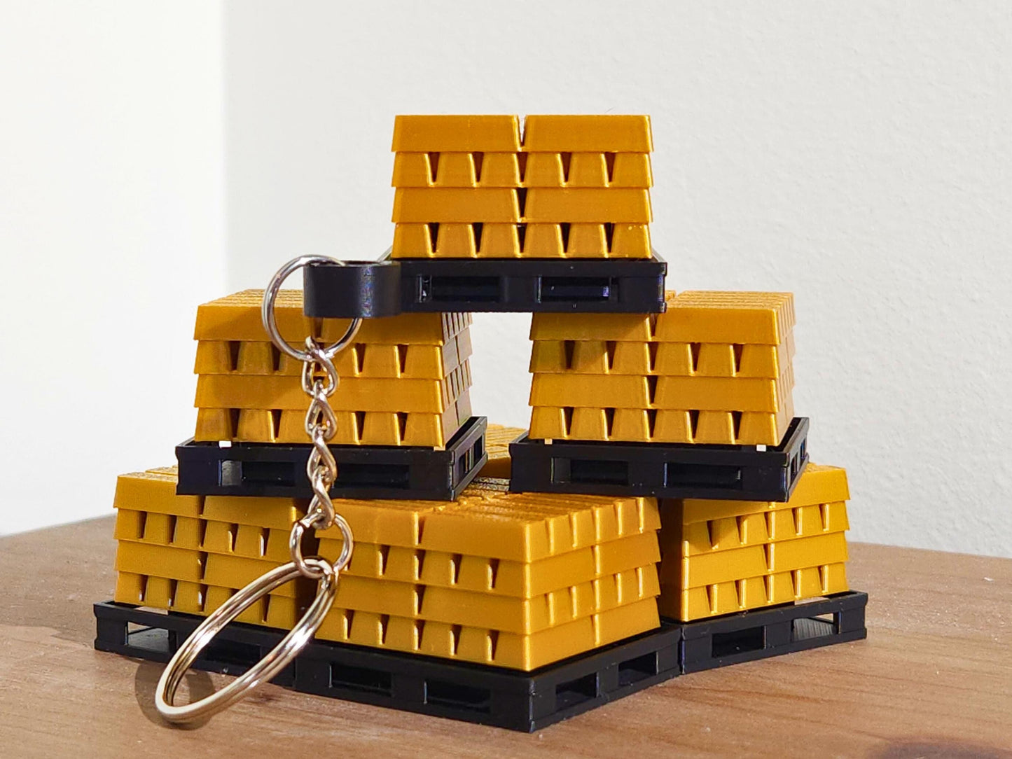 A close up picture of a set of gold bar keychains from Fortnite, stacked on top of each other. The top has a mechanical clicker that can be used for anti-stress or as a fidget toy.