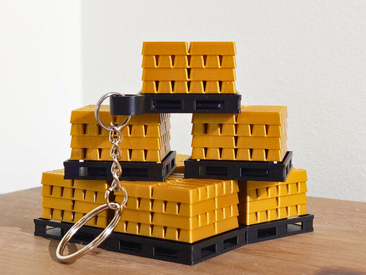 A close up picture of a set of gold bar keychains from Fortnite, stacked on top of each other. The top has a mechanical clicker that can be used for anti-stress or as a fidget toy.