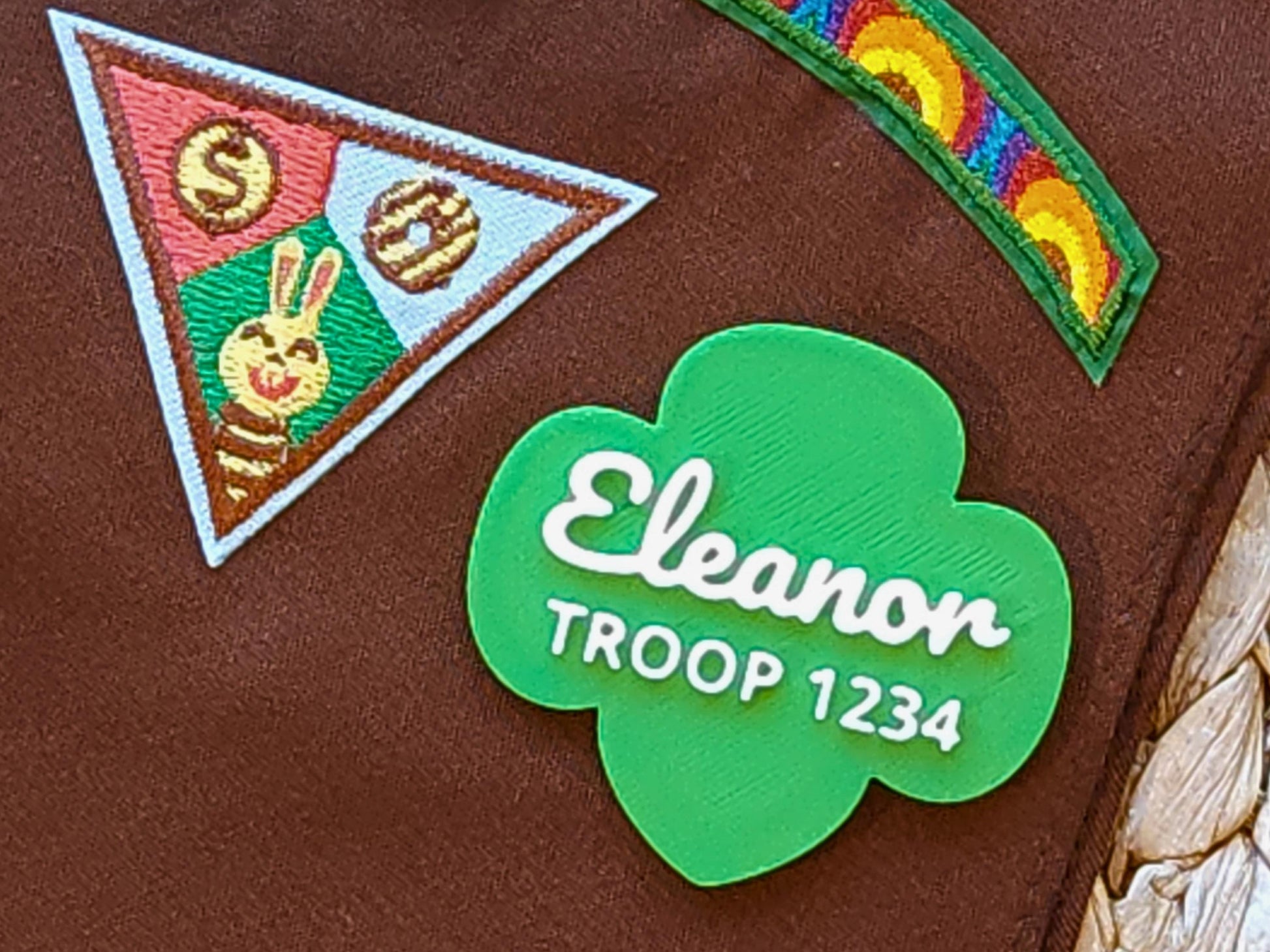 Girl Scout Brownie pin with green trefoil design, personalized with name and troop number, shown on a Brownie sash with earned patches—perfect for troop swaps or recognition gifts.