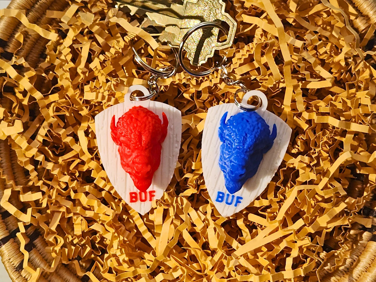 Additional flat lay of both buffalo keychains styled with keys for scale and presentation.