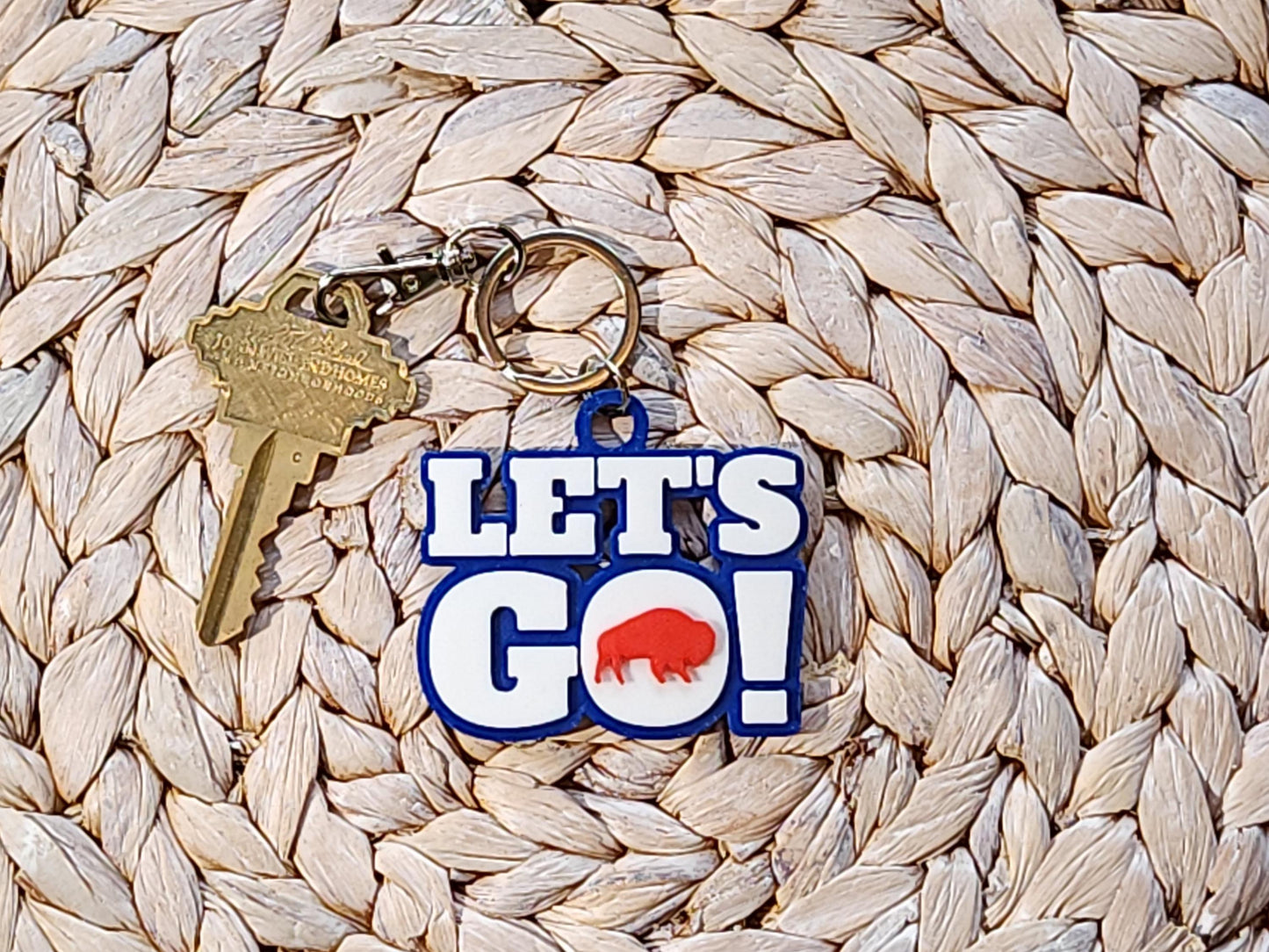 View of Let's Go Buffalo football keychain on a woven background.