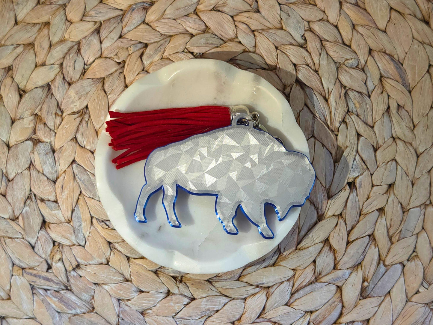 Unique icy buffalo keychain styled on a woven background – 3D printed charm with red tassel makes a great gift for minimalist football fans.