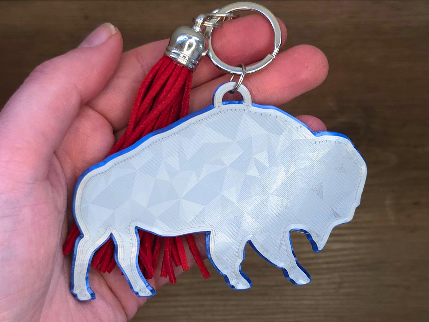 Minimalist buffalo bag tag with geometric texture and red tassel shown in hand for scale – lightweight and durable purse charm.
