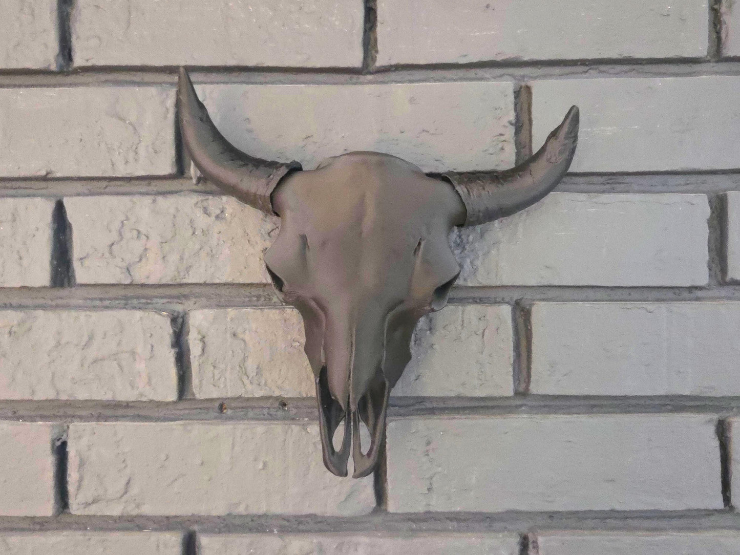 A black bison skull is hung on a black brick wall, showcasing ornate details.