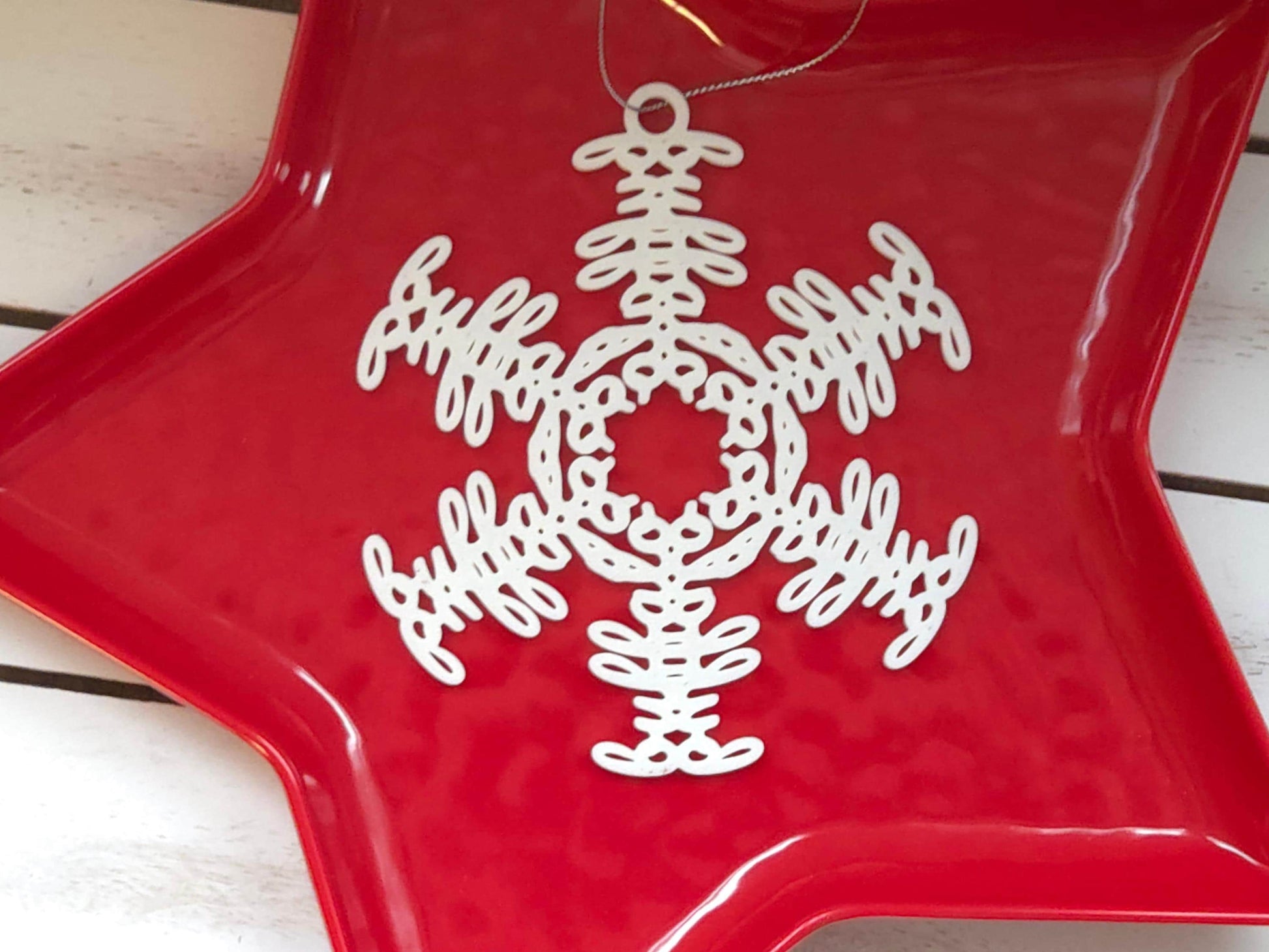 White snowflake christmas ornament that spells the word "Buffalo" displayed in a red tray on a white wooden background.