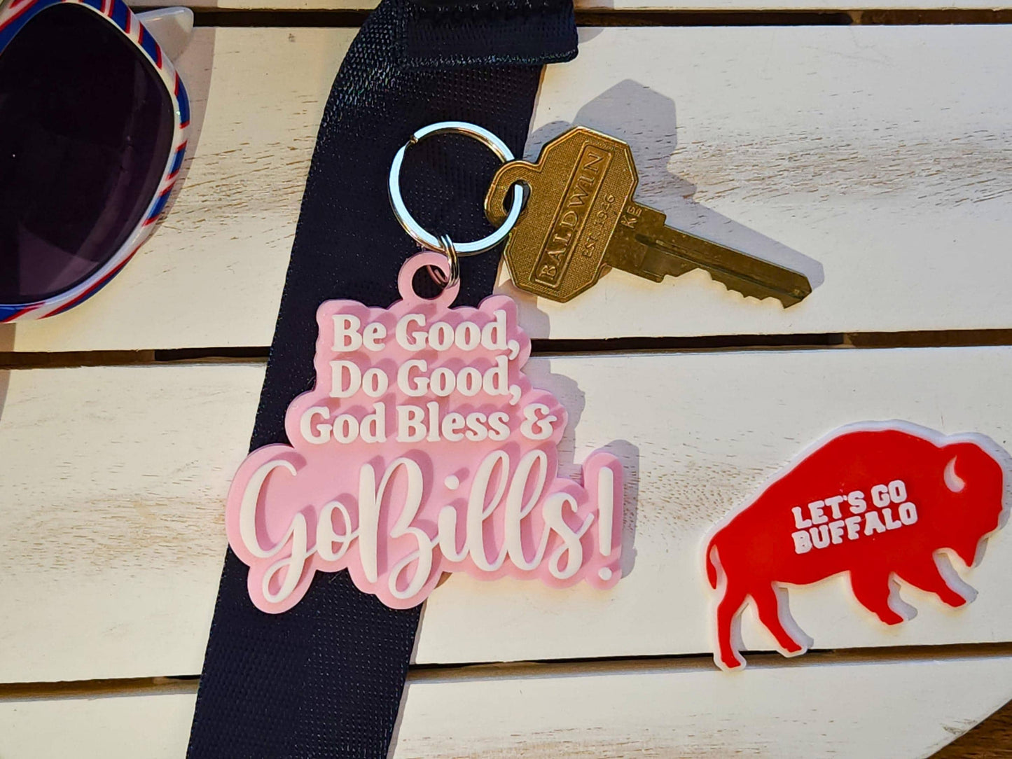 A pink keychain with white letters that says Be Good Do good God Bless Go Bills in honor of Josh Allen&#39;s MVP speech.