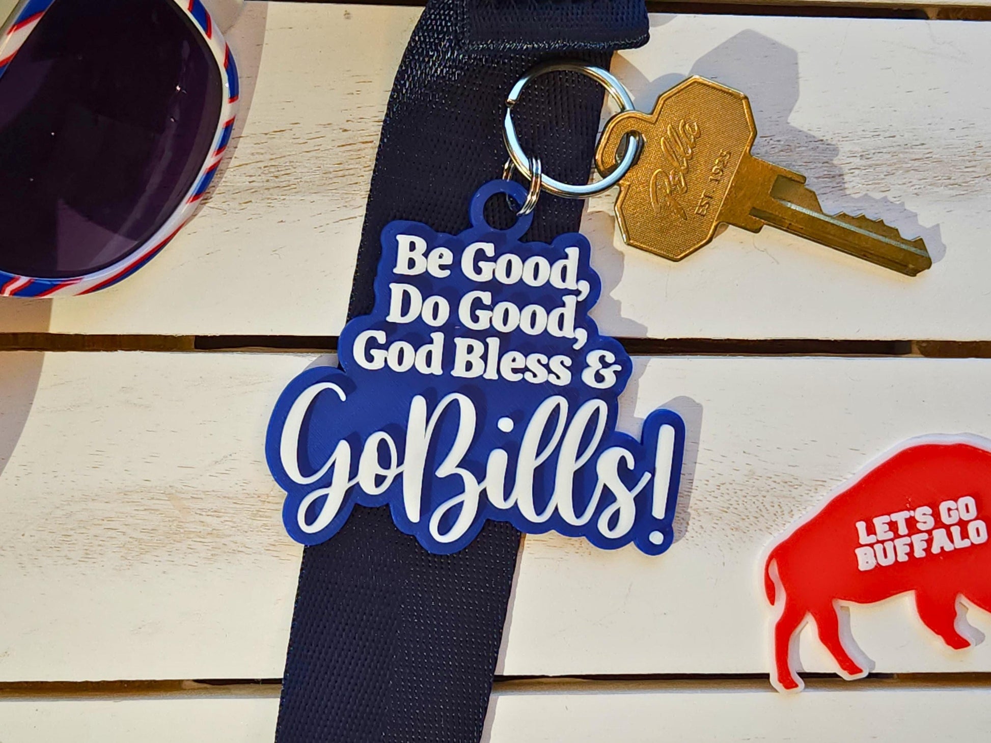 A blue keychain with white letters that says Be Good Do good God Bless Go Bills in honor of Josh Allen&#39;s MVP speech.