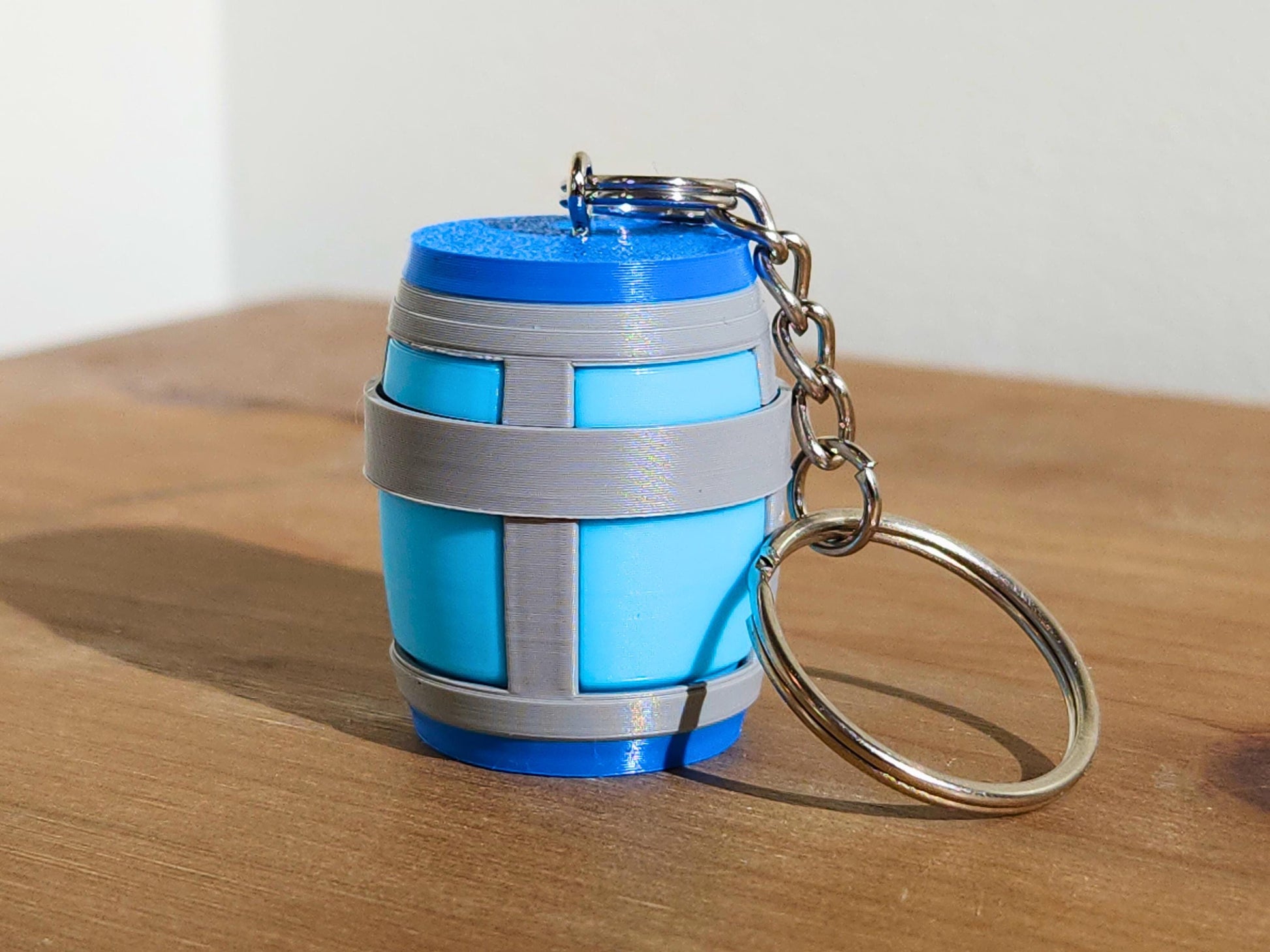 A close up picture of a single Chug Jug keychain from Fortnite, sitting on a table. The top has a mechanical clicker that can be used for anti-stress or fidgeting.