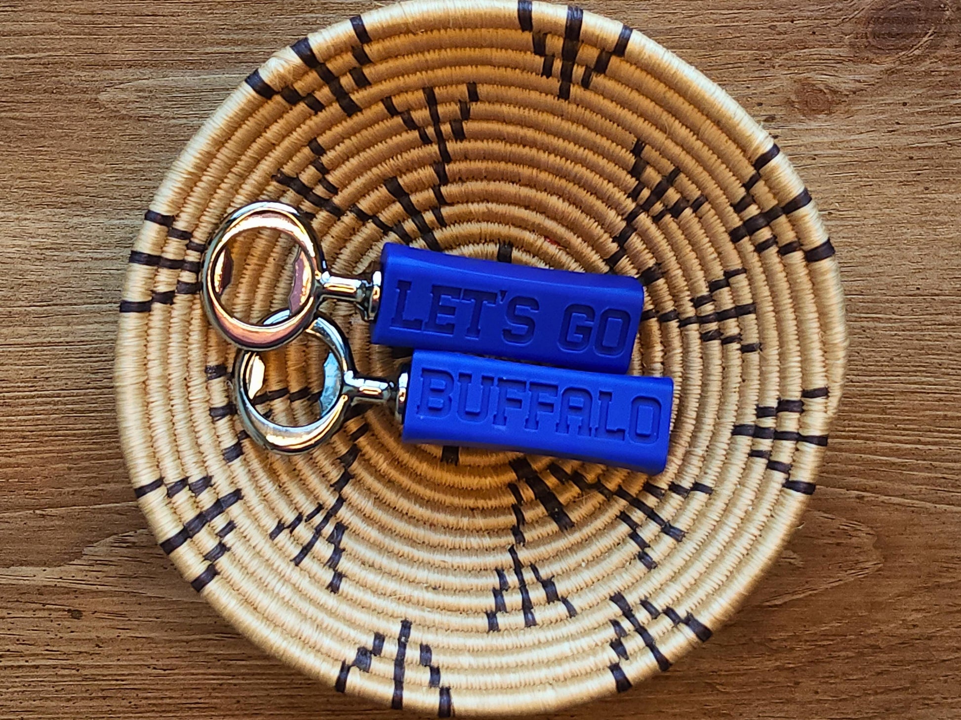 Two buffalo bills bottle openers side by side on a wooden surface, showcasing their compact and stylish design. they say let&#39;s go buffalo on them.