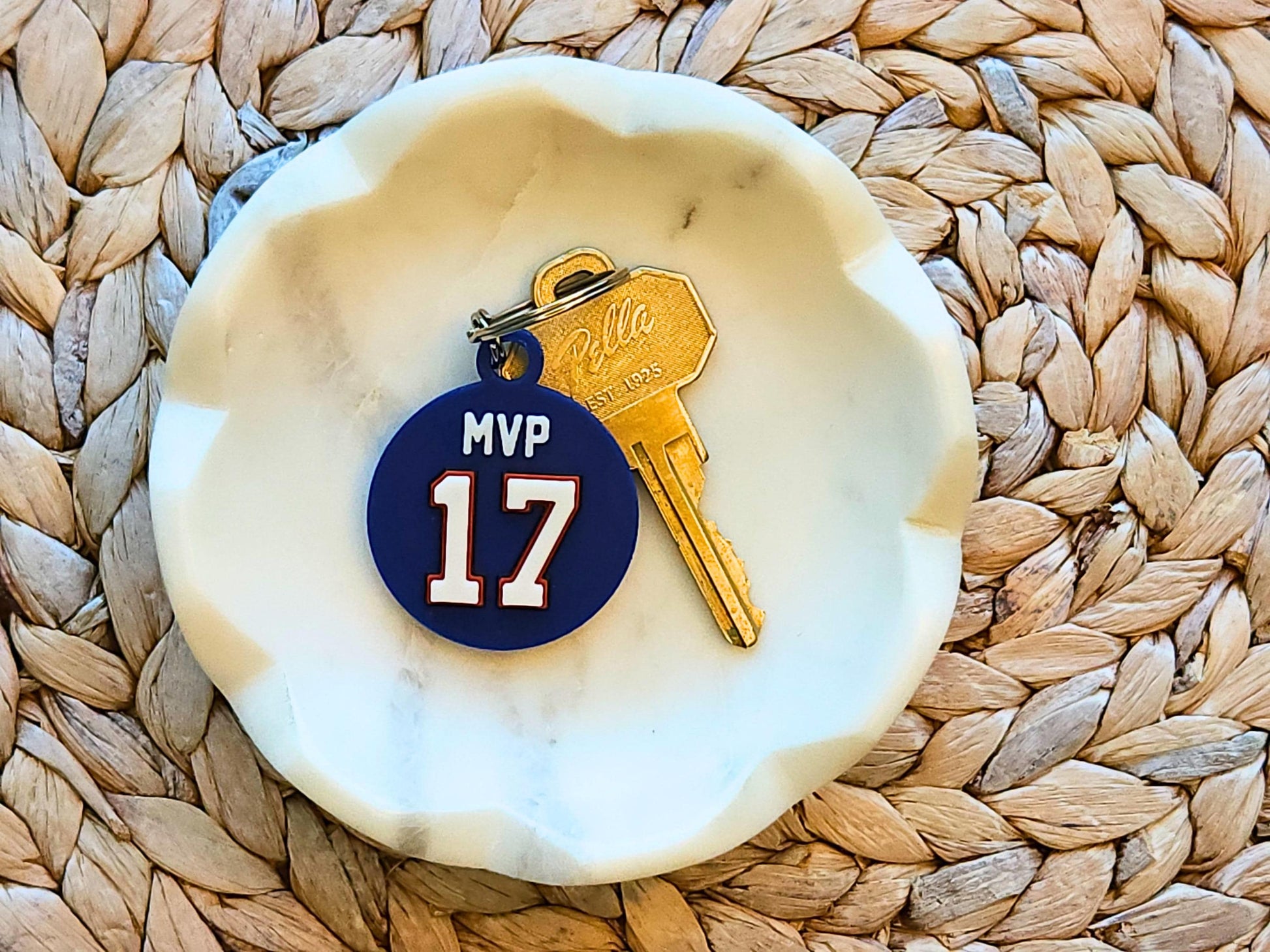 A blue keychain featuring the number 17 and phrase MVP in a white bowl to commemorate Josh Allen&#39;s 2024 MVP Season with the Buffalo Bills.