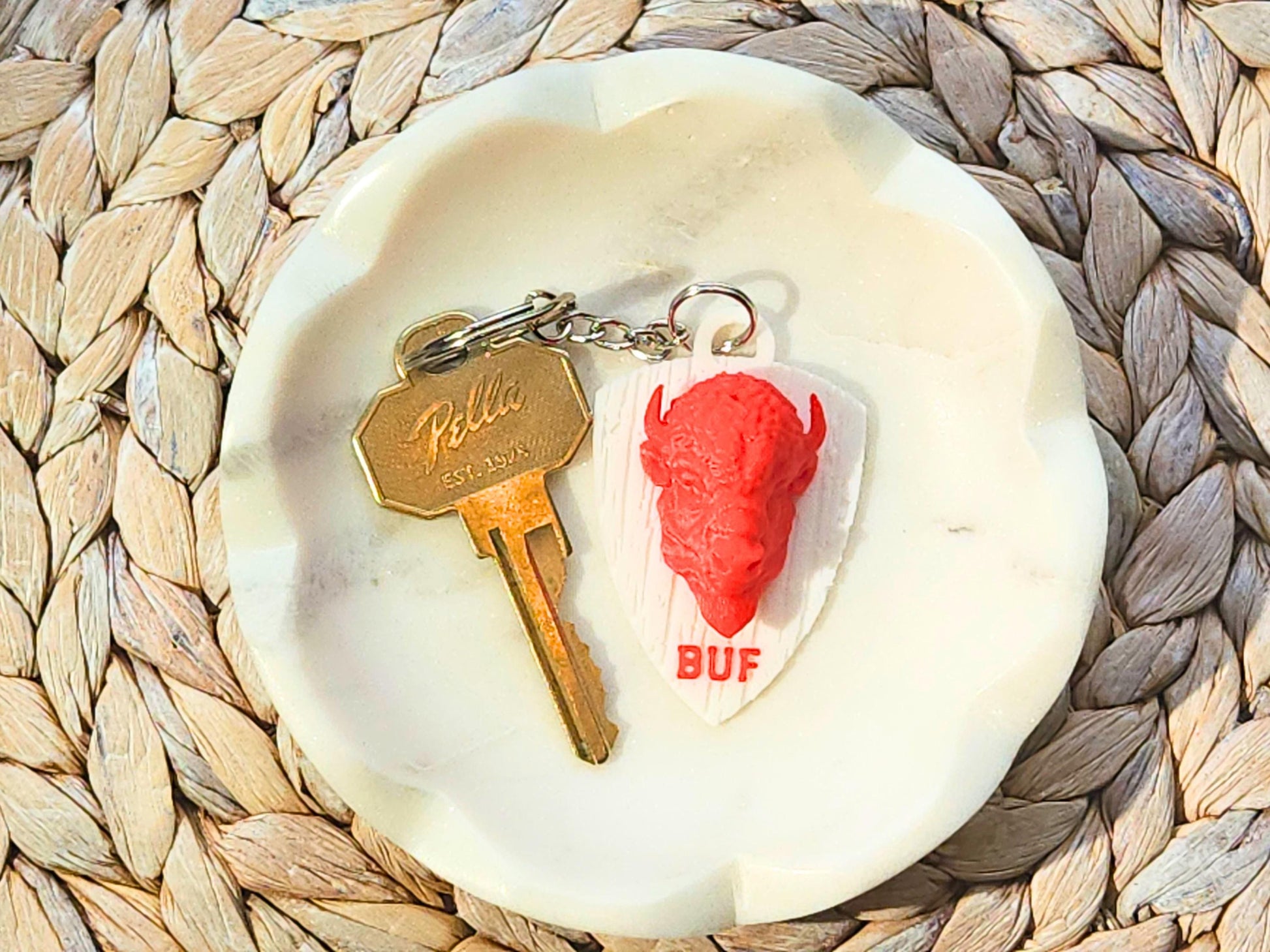 Red buffalo keychain on a dish next to a vintage-style brass key.