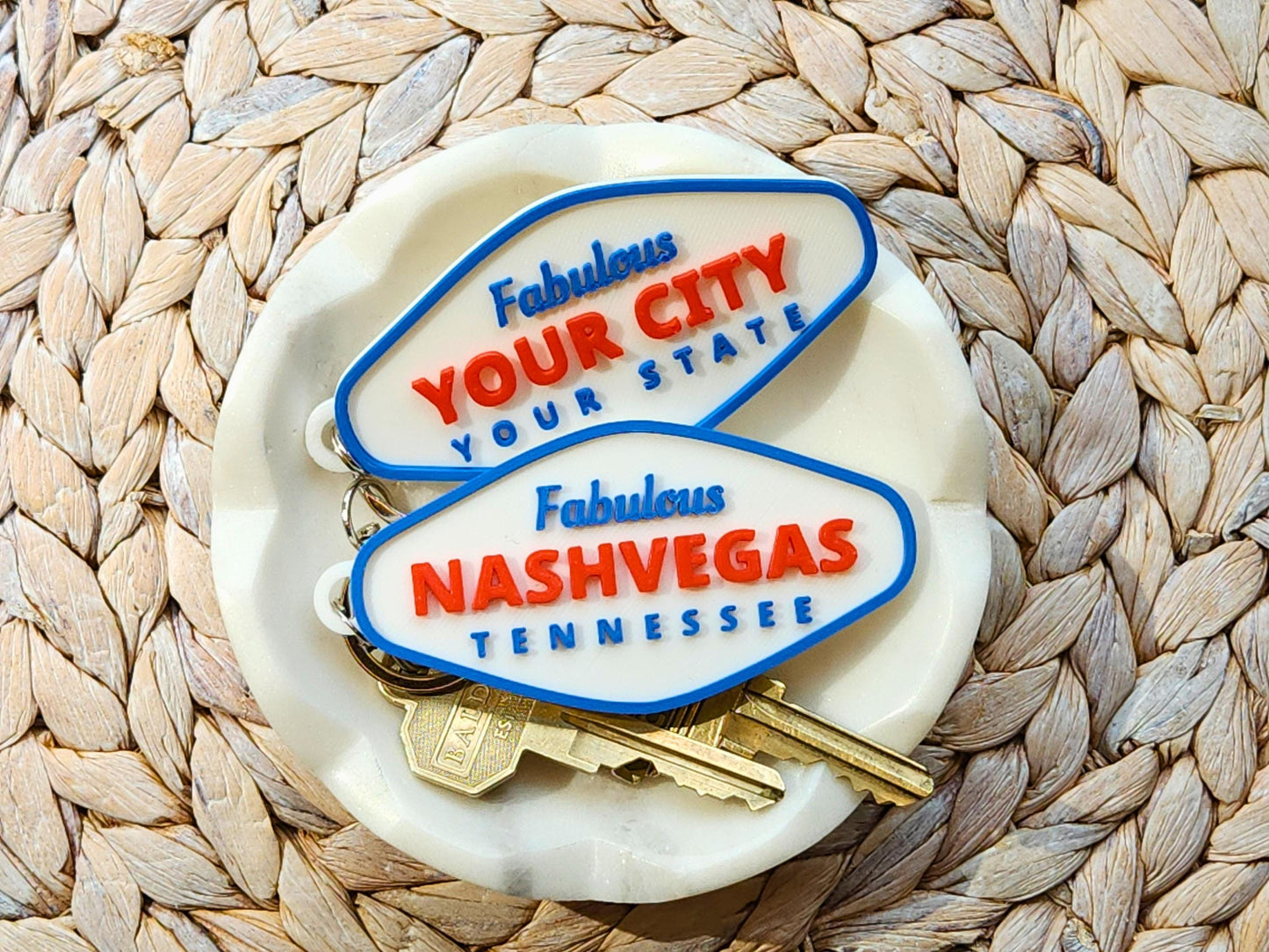 Set of custom Fabulous city and state keychains, including Nashvegas and YOUR CITY design, displayed in a ceramic catchall dish