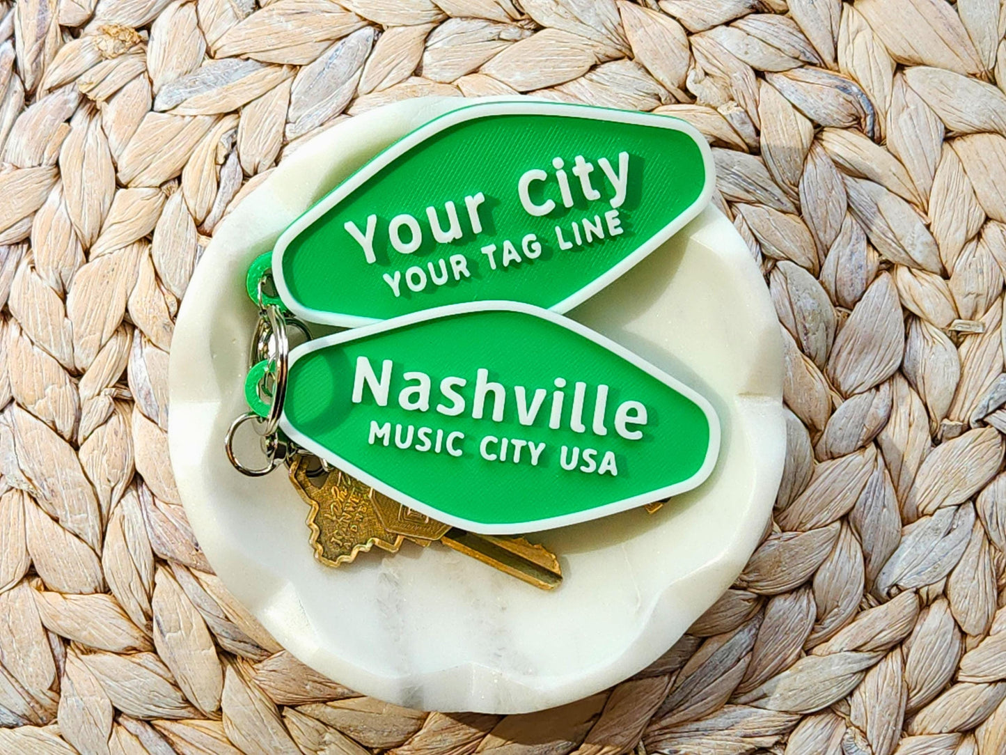 Customizable and Nashville keychains on a woven tray and white dish, stacked neatly with attached keyrings and keys.