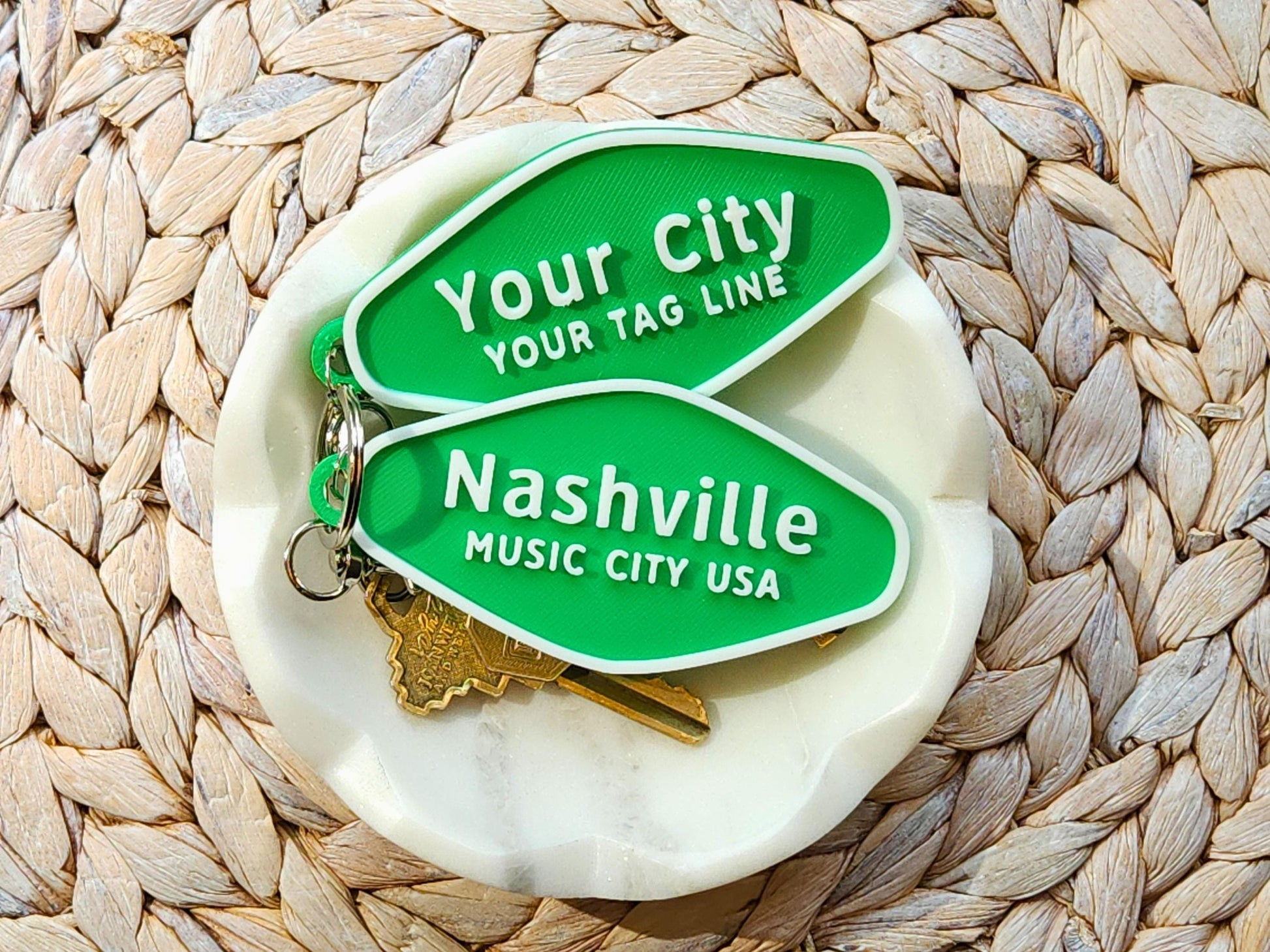 Customizable and Nashville keychains on a woven tray and white dish, stacked neatly with attached keyrings and keys.