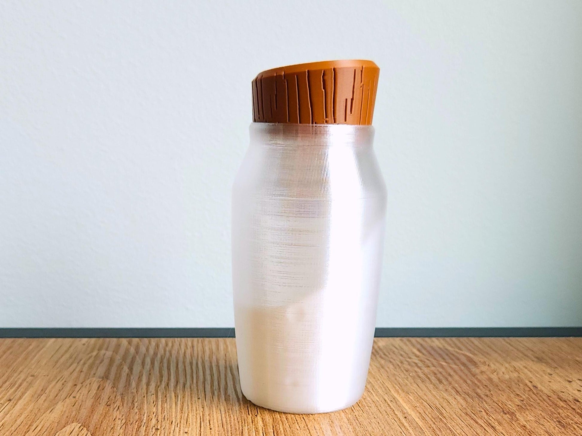 A straight-on view of the potion bottle lamp with its cap attached, standing alone on a wood surface with a neutral white wall background.
