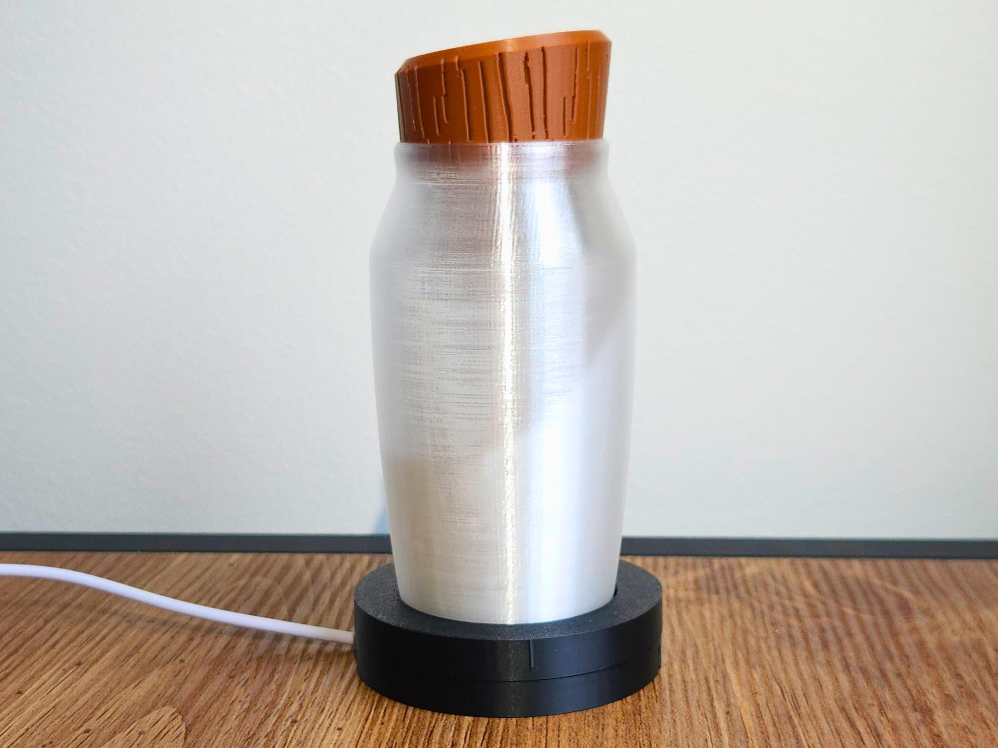 A close-up of a color-changing potion bottle lamp with a brown wood-textured cap, placed on a black circular LED base, against a white background.