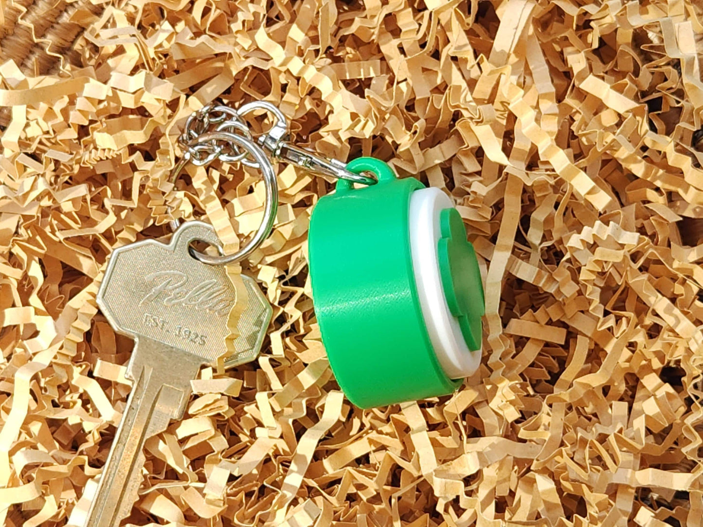 Side view of the green keychain, emphasizing the thickness and clicker button structure.