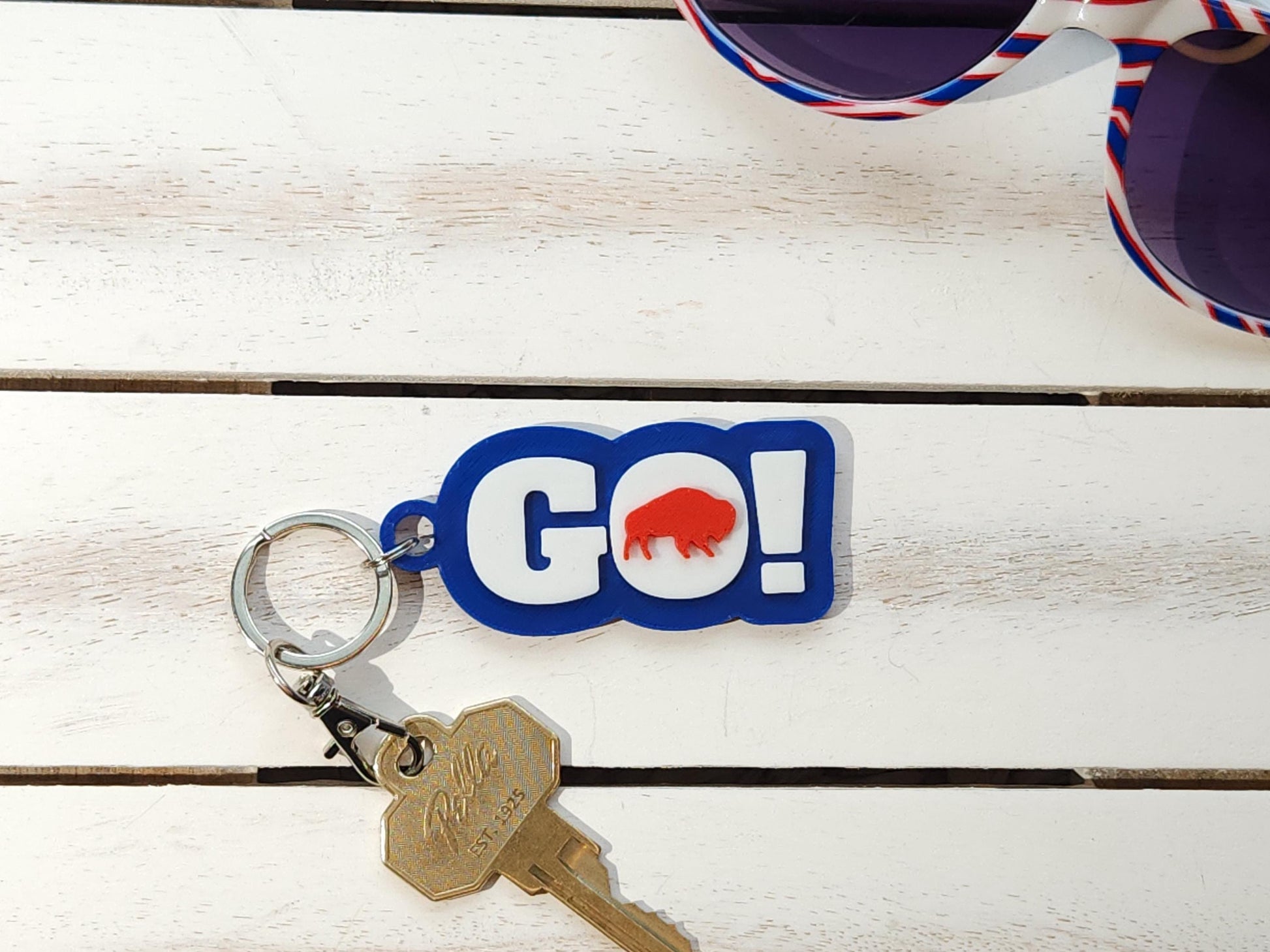 GO BILLS! buffalo football keychain on white wood background with sunglasses nearby