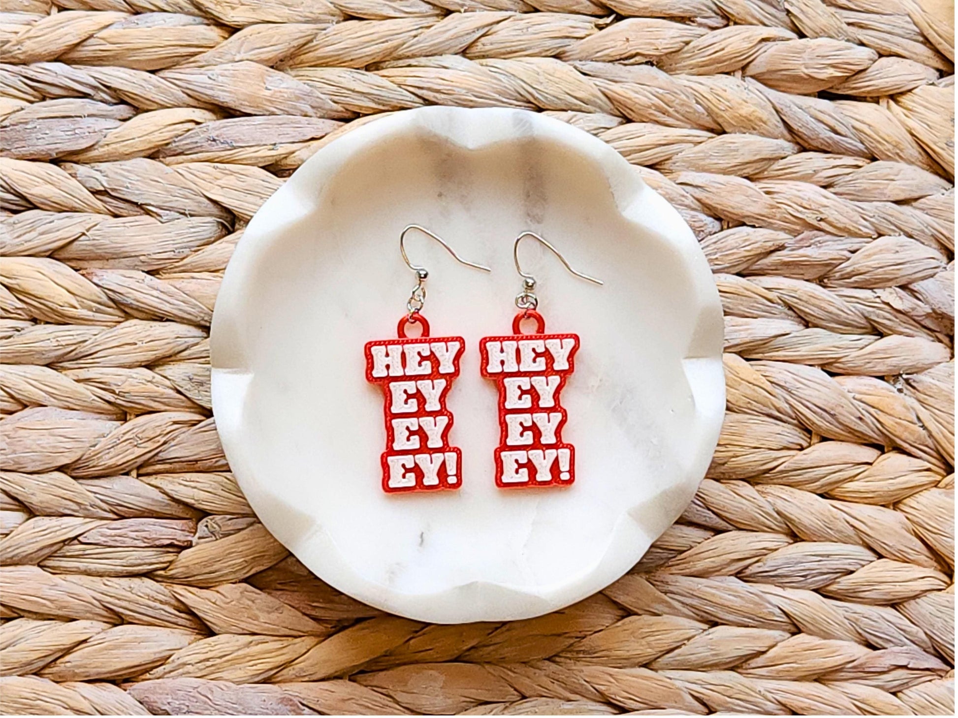 Red Buffalo Bills “Hey Ey Ey Ey” 3D printed earrings on white ceramic dish – lightweight NFL game day fan jewelry for women.