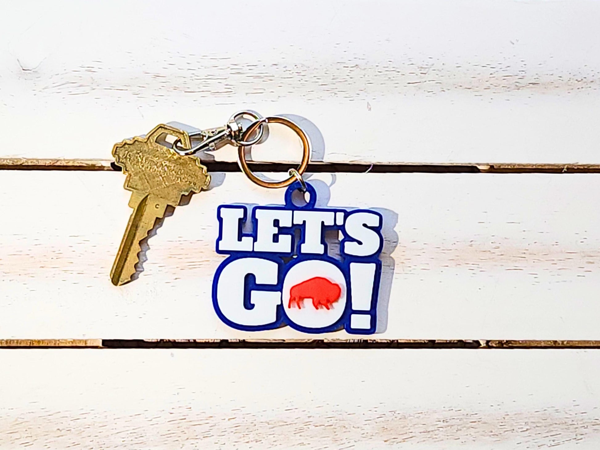 View of Let&#39;s Go Buffalo football keychain on a wooden background.