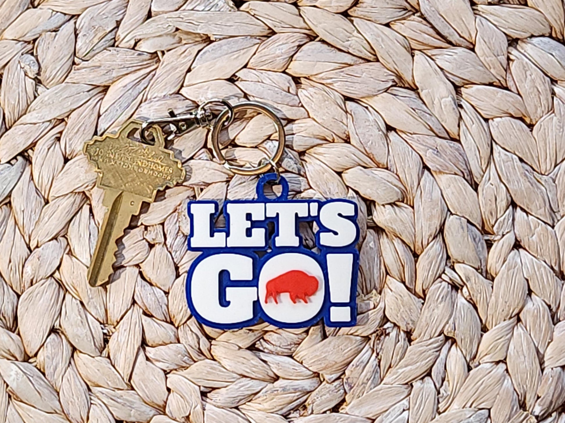 View of Let&#39;s Go Buffalo football keychain on a woven background.