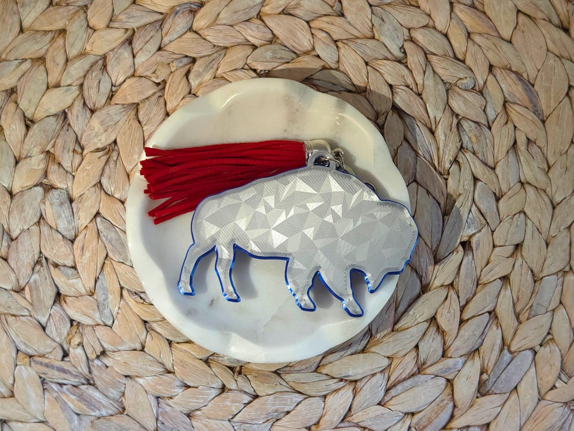 Unique icy buffalo keychain styled on a woven background – 3D printed charm with red tassel makes a great gift for minimalist football fans.
