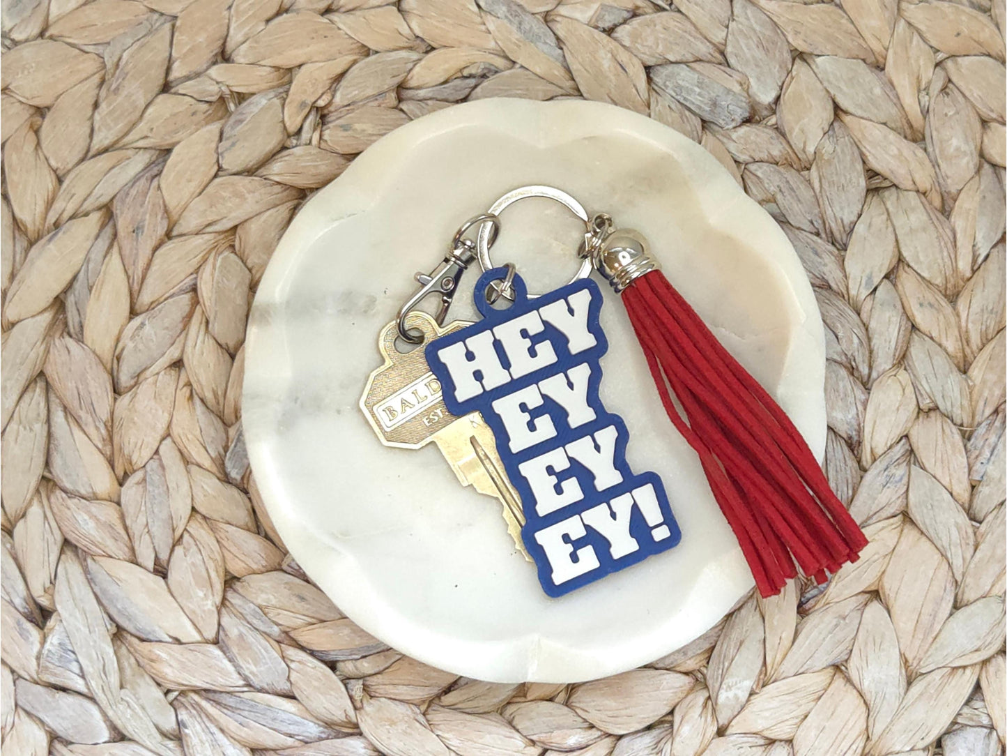 Buffalo football keychain featuring the phrase Hey Ey Ey Ey on a blue background with a red tassel.