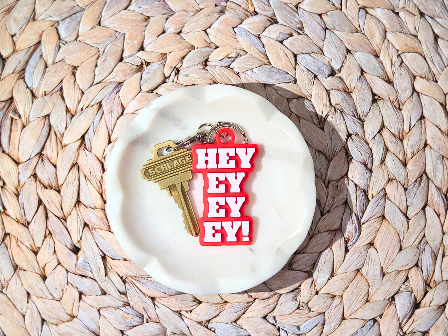 Buffalo football keychain featuring the phrase Hey Ey Ey Ey on a red background in a white marble dish.