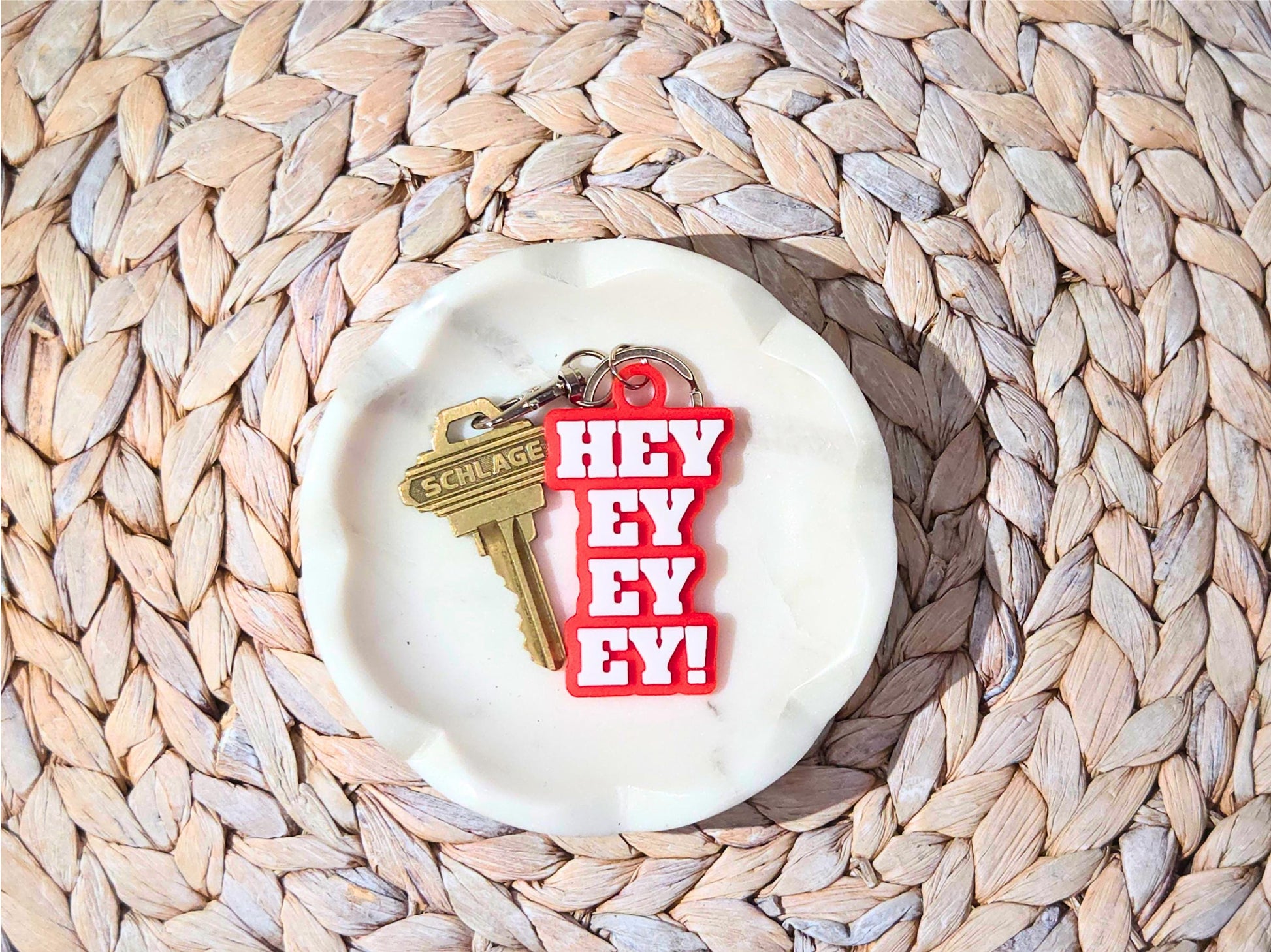 Buffalo football keychain featuring the phrase Hey Ey Ey Ey on a red background in a white marble dish.