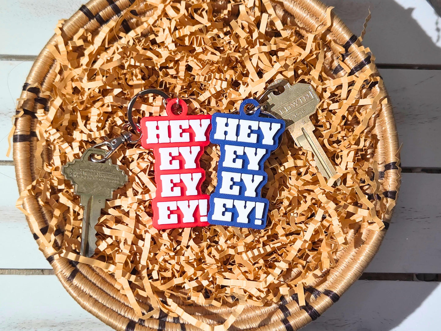 Set of Buffalo football keychains featuring the phrase Hey Ey Ey Ey on a red and background in a decorative bowl of kraft paper.