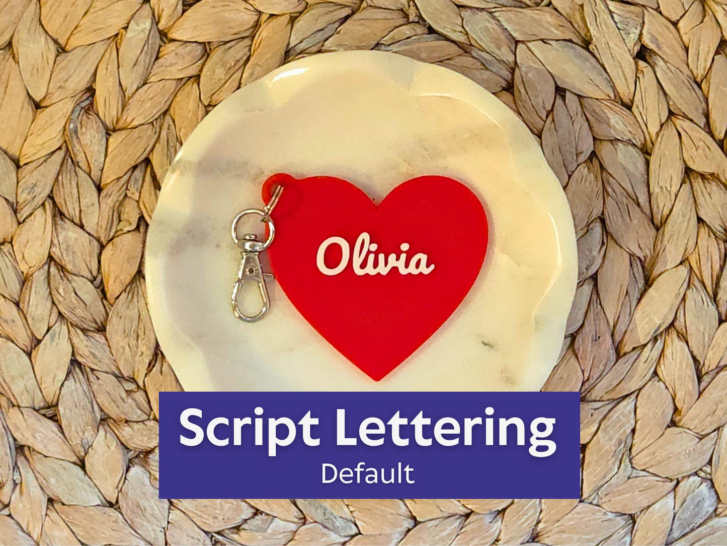 The front of the personalized heart keychain is pictured in a white dish on a woven background. It can also be used as a zipper pull or bag charm. It features the child's name, in this case the name Olivia in script font.