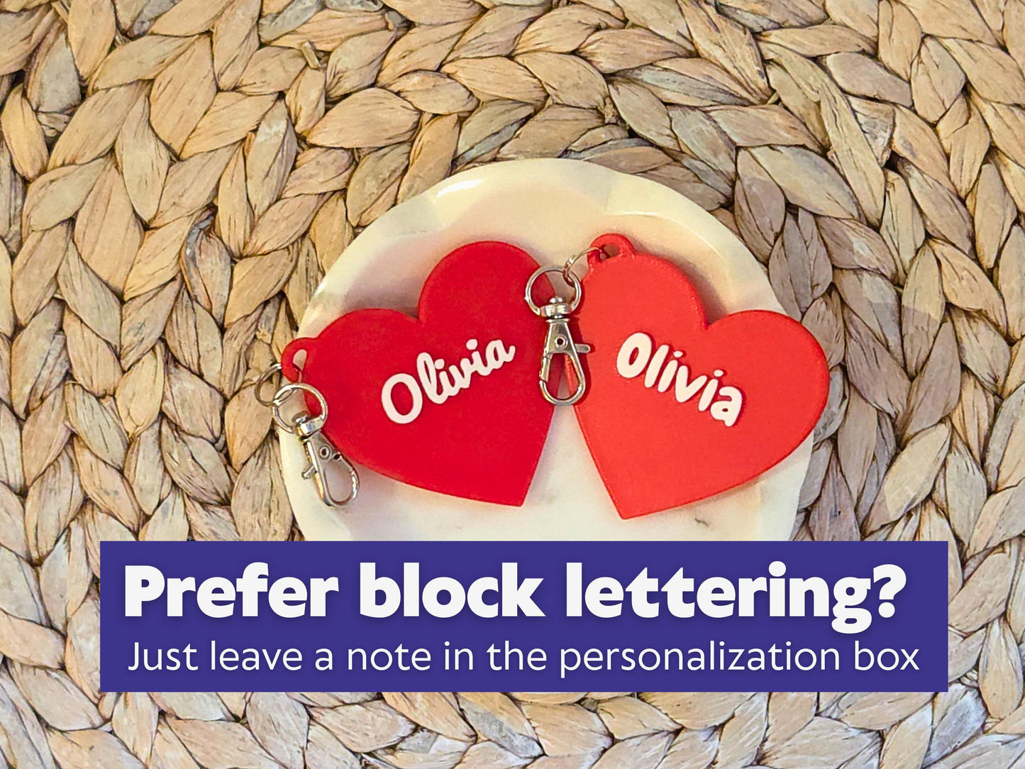 Two classroom valentine keychains are pictured in a white dish on a woven background. One says Olivia in a script font, one says Olivia in a block font which is easier for small children to read.