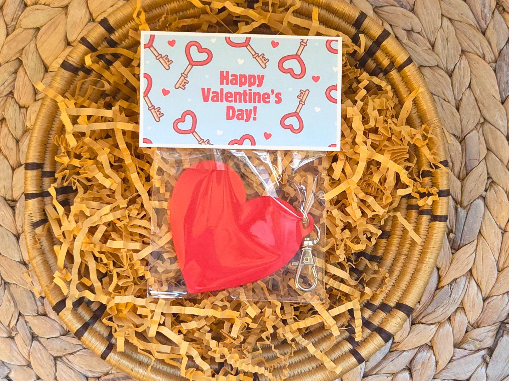 The back of the Valentine's Day gift is pictured in kraft paper on a woven background. The back is blank and the bag topper says "Happy Valentine's Day. The item could also be used as a zipper pull or bag charm.