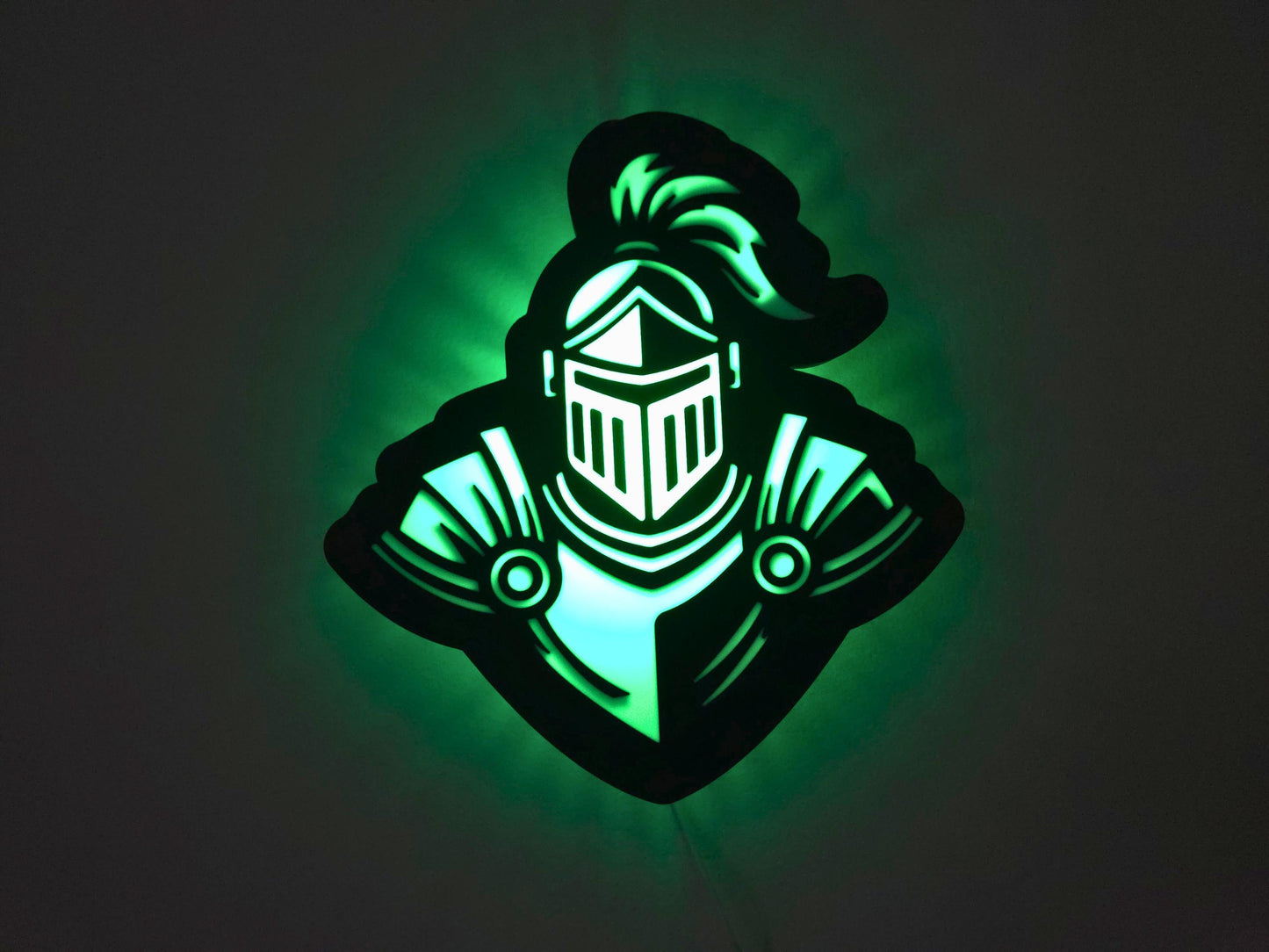 The knight lamp is illuminated in green on a wall with the lights off.