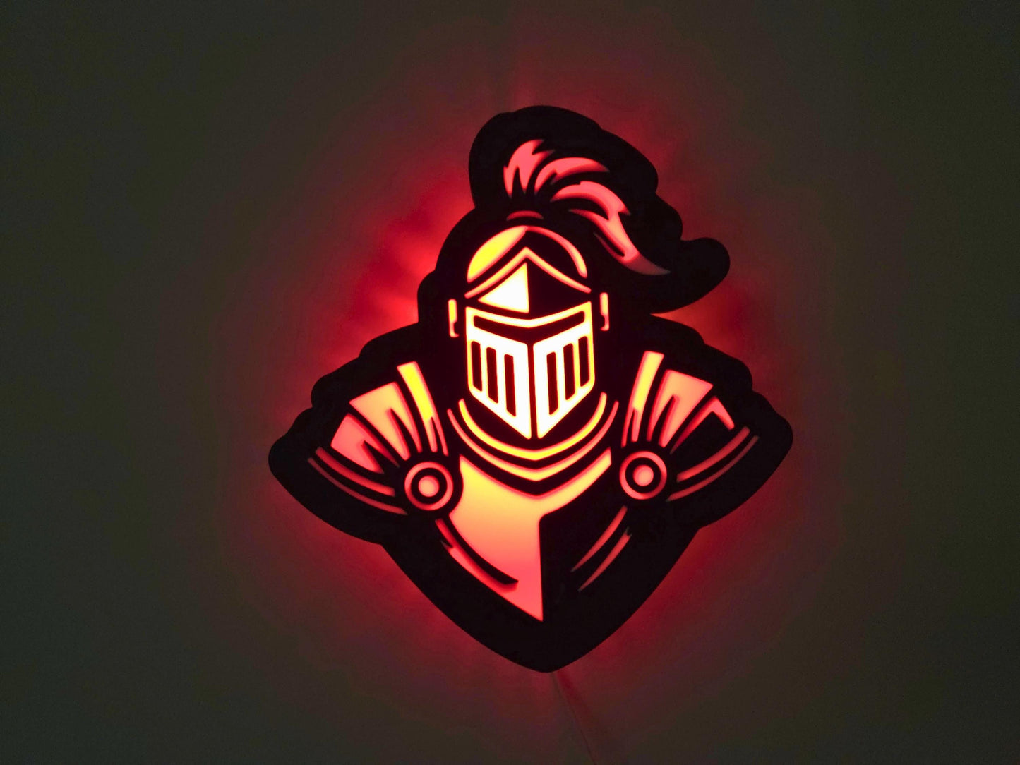 The knight lamp is illuminated in red on a wall with the lights off.