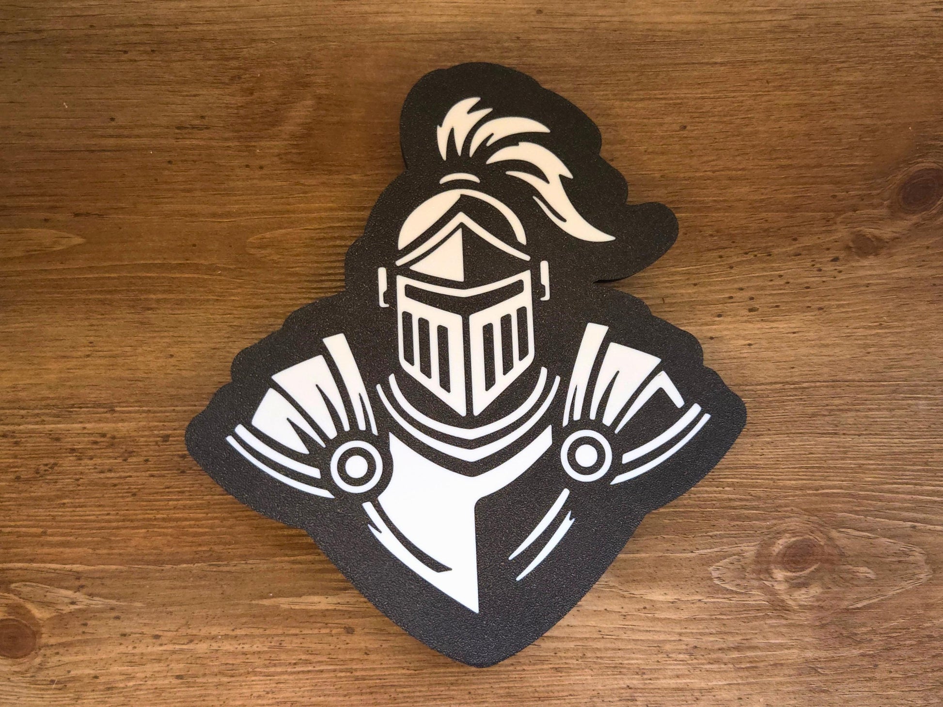 The front of the lamp is pictured on a wooden background. The lamp is black and white and features a knight mascot.