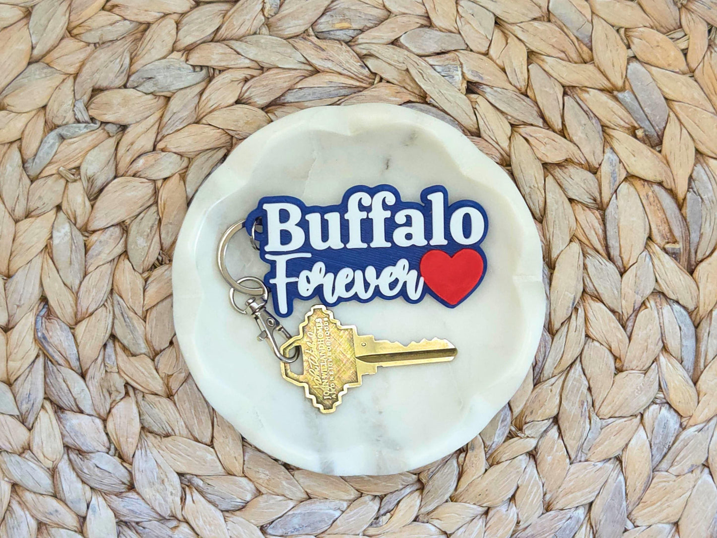 Buffalo Forever keychain featured in a white dish on a woven background. A key is shown for scale.