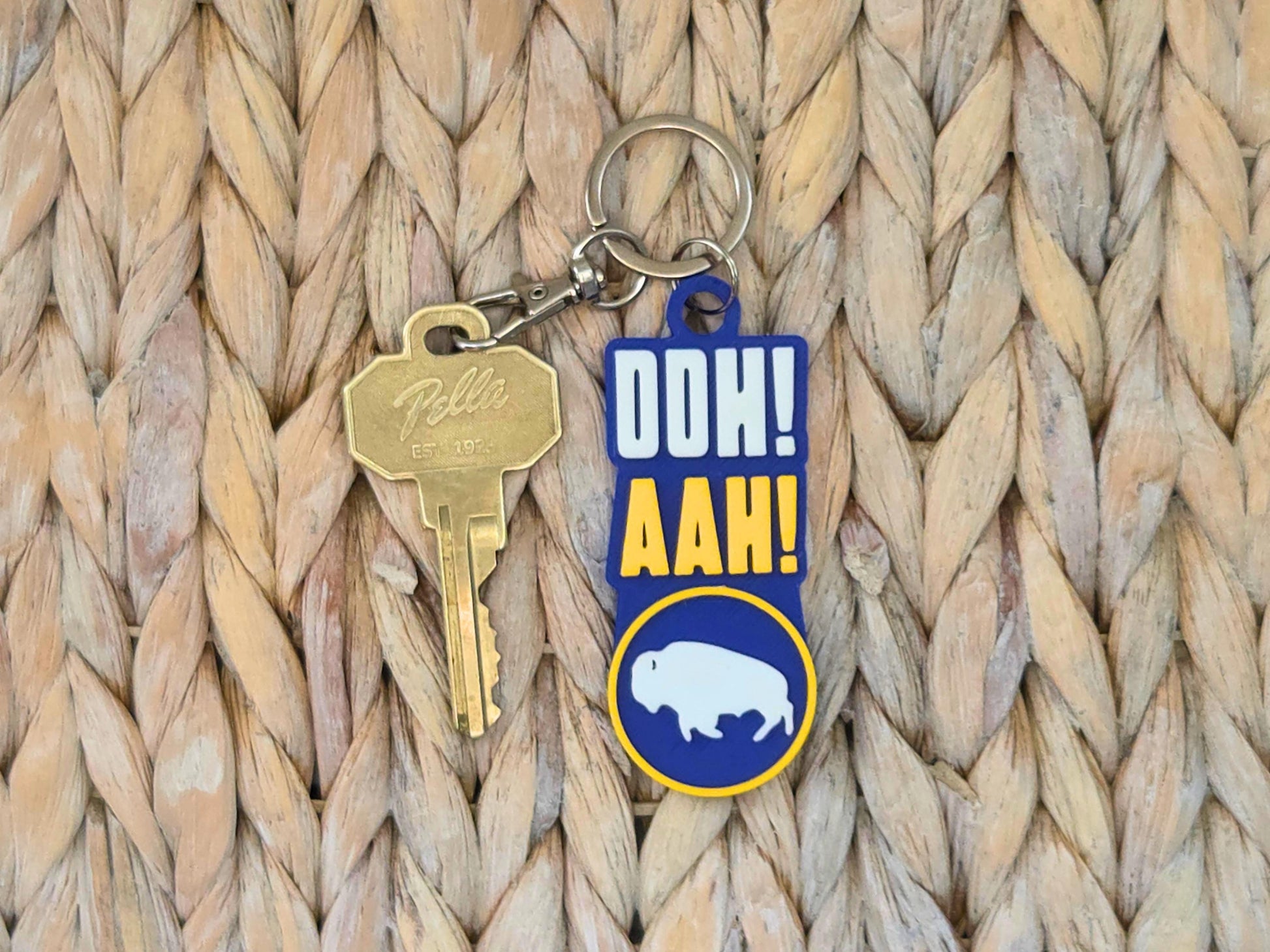 Close-up of a durable 3D-printed "Ooh Aah" Buffalo hockey bag tag on a natural woven straw surface.