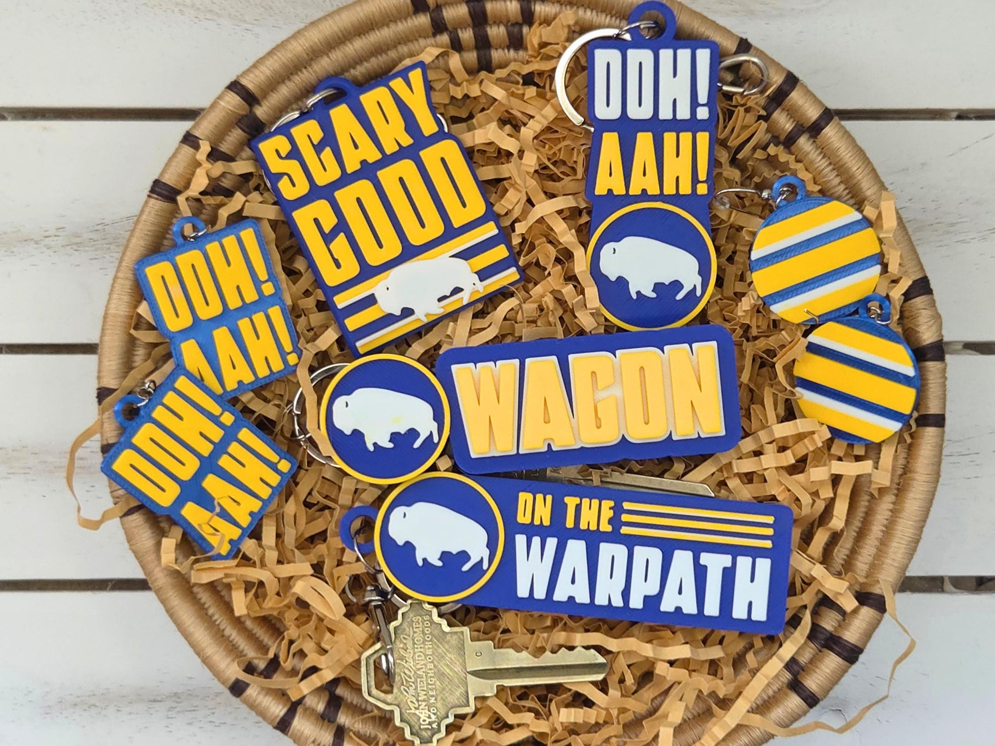 Flat lay of Buffalo hockey fan accessories including "Wagon," "Ooh Aah," and "Scary Good" keychains and earrings.