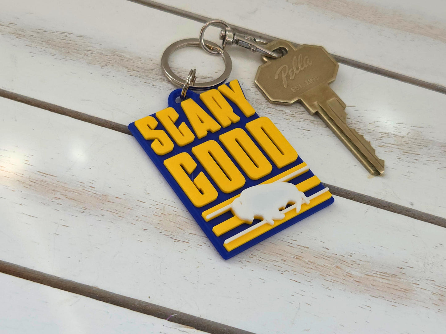 Buffalo "Scary Good" fan keychain with a silver quick-clip and house key on a white wood surface for size scale.