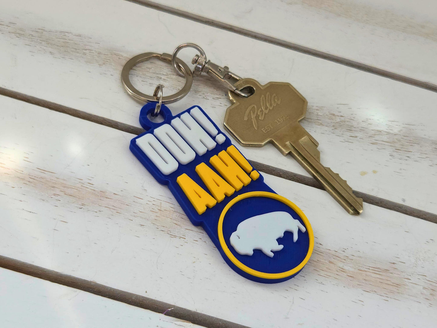 Buffalo "Ooh Aah" chant keychain with lobster claw clip and house key on a white wood background.