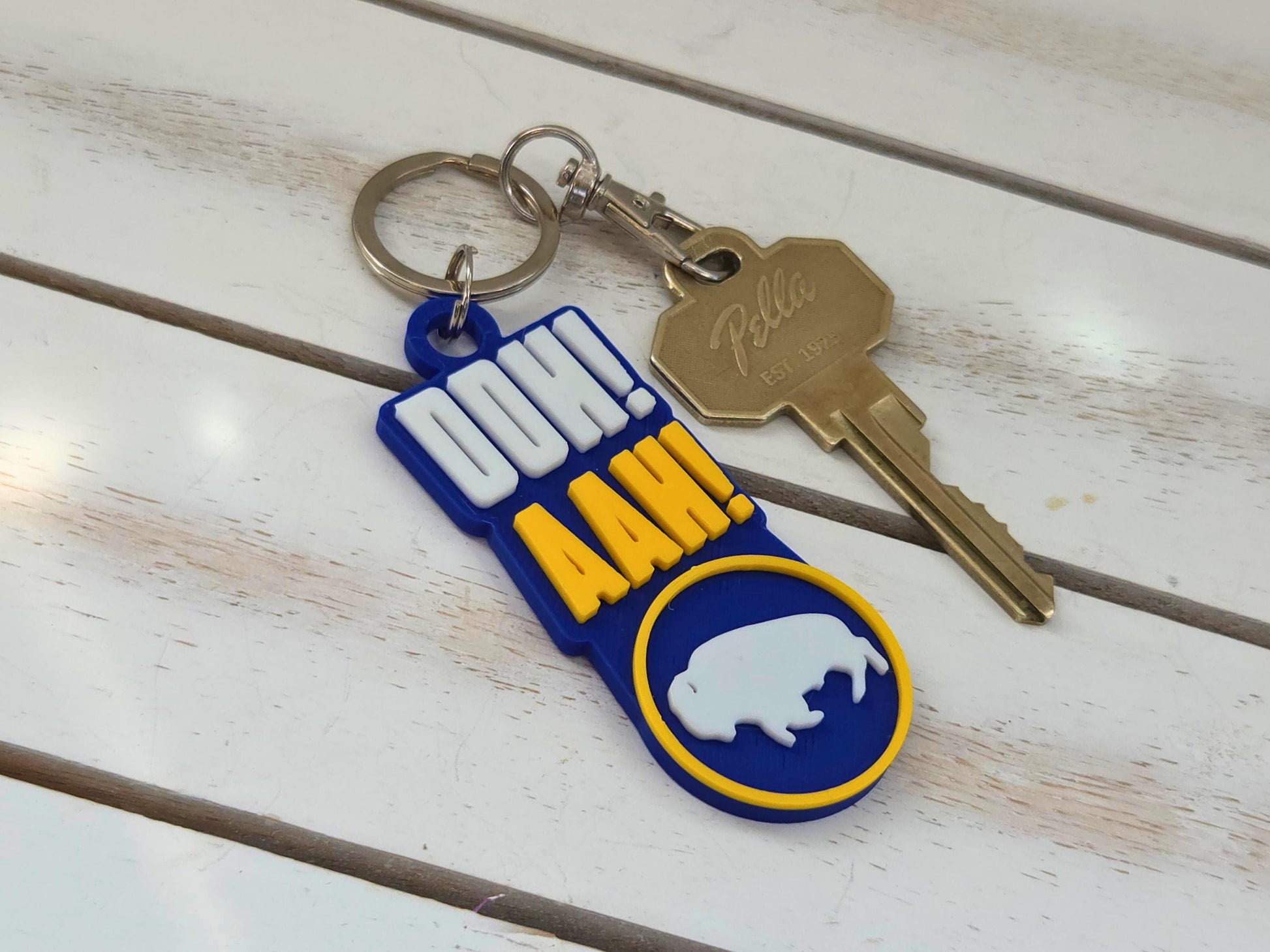 Buffalo "Ooh Aah" chant keychain with lobster claw clip and house key on a white wood background.
